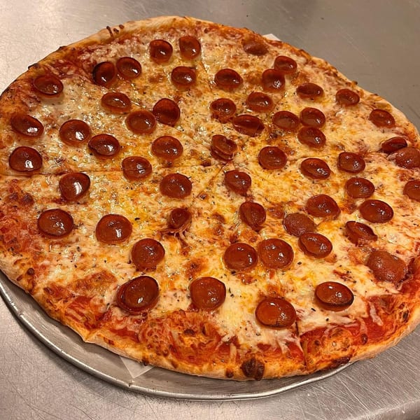 A whole pepperoni pizza from Capo's Pizzeria, sliced and ready to eat on a metal tray.