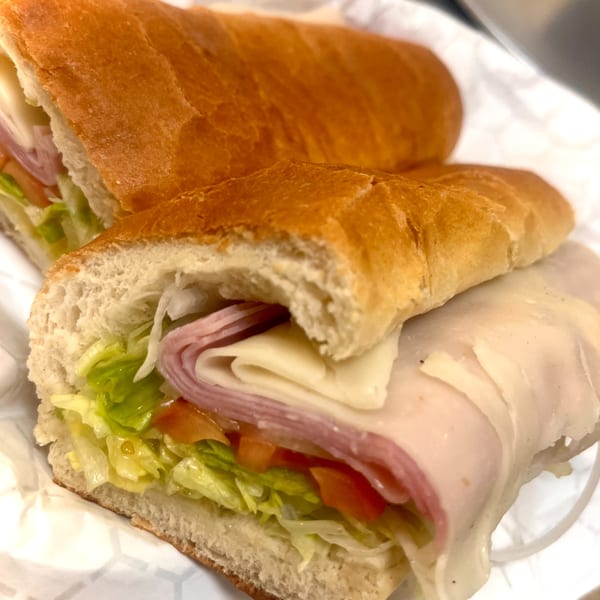 A Capo's Pizzeria Italian sub sandwich with meat, cheese, lettuce, and tomato.