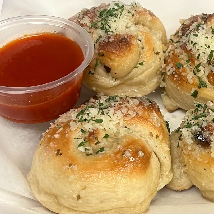 Garlic knots topped with parmesan cheese and parsley, served with a side of marinara sauce.