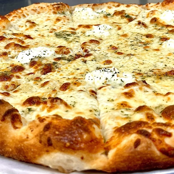Close-up of a Capo's Pizzeria white pizza, topped with mozzarella, ricotta, and herbs.